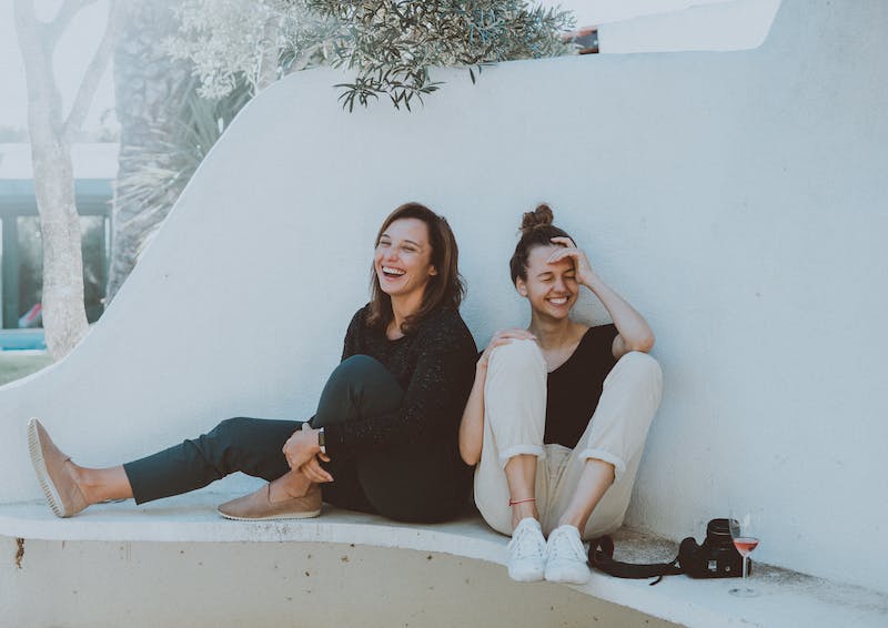 Two people sitting on a ledge and laughing.