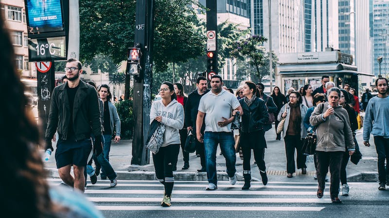 A group of people crossing the street on a cross walk.