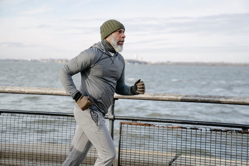 A man running near the ocean on a pier.