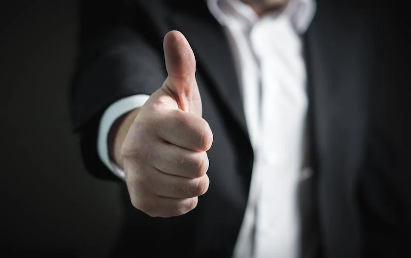 A man in a suit giving the thumbs up.