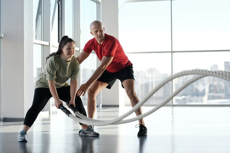 A man and woman are using ropes to work out.