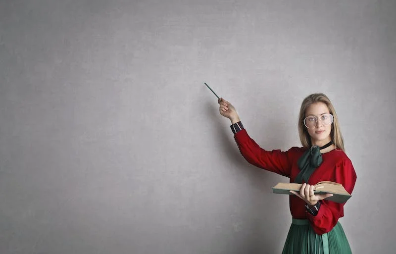 A woman in red shirt pointing to the wall.