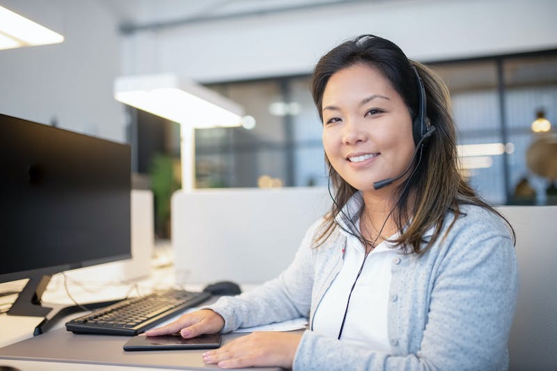 A woman sitting at her desk with headphones on.