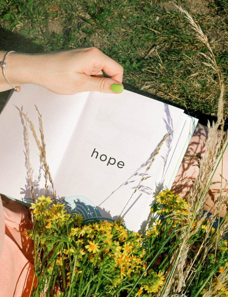 A person holding an open book with the word hope written on it.