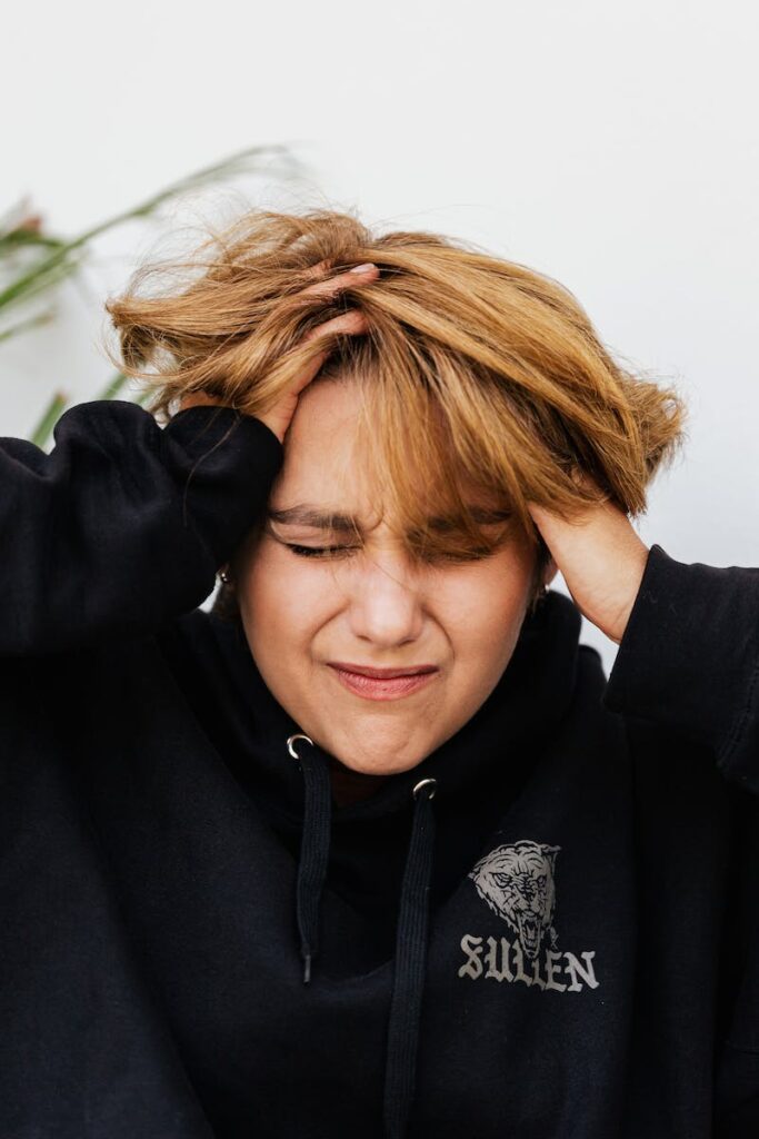 A woman holding her head in front of her face.