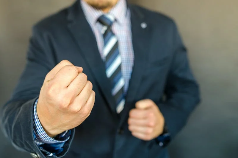 A man in a suit and tie holding his hands up.