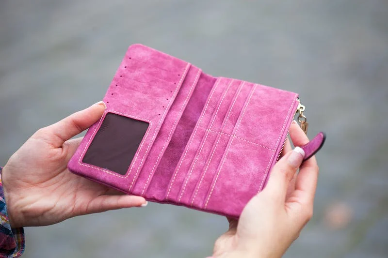 A person holding onto a pink wallet