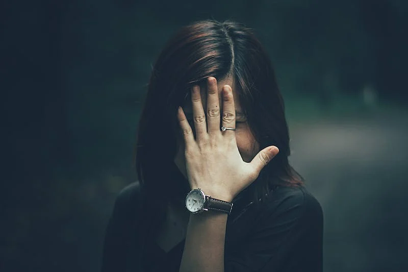 A woman covering her face with her hand.