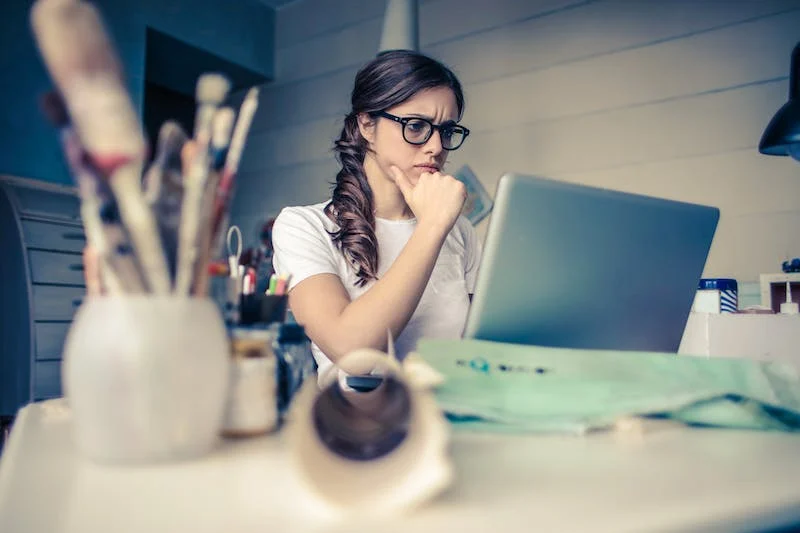 A woman sitting at a table with her laptop.