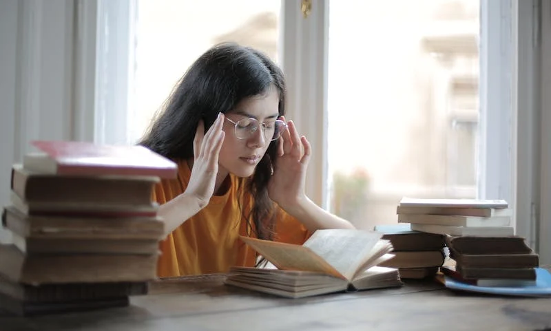 A woman sitting at a table reading a book.