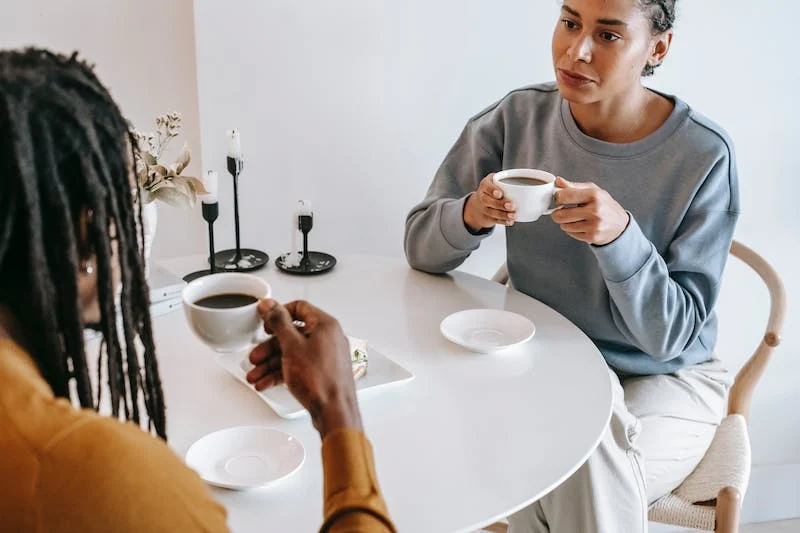 Two people sitting at a table with cups of coffee.