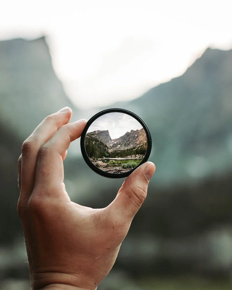 A person holding a camera lens in their hand.