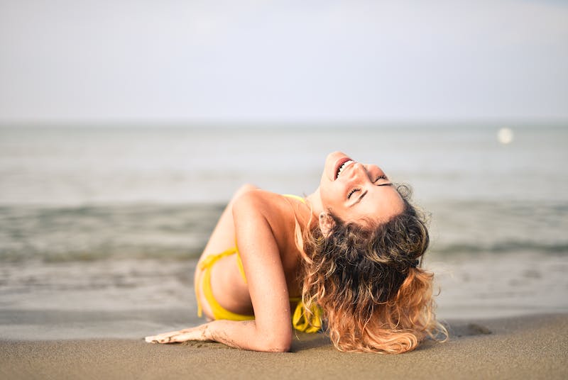 A woman laying on the beach in front of the ocean.