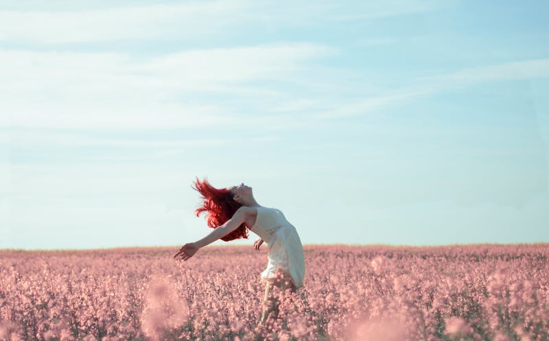 A woman in white dress standing on top of pink flower field.