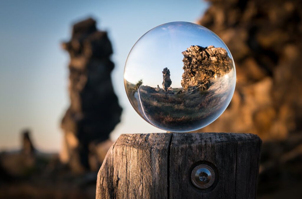 A glass ball is sitting on top of a wooden post.