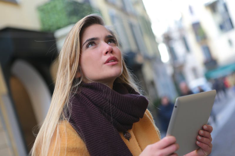 A woman in yellow jacket holding a tablet.