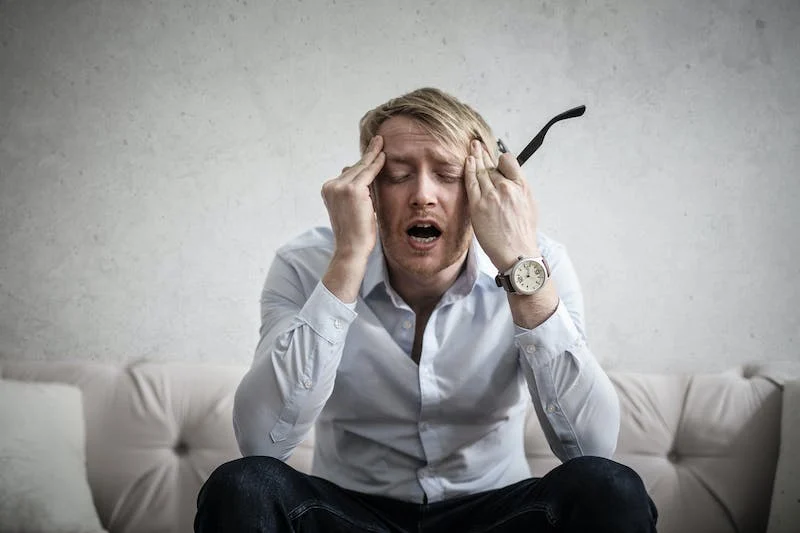 A man sitting on the ground with his hands in his head.